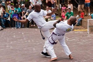 Two men in white shirts and black pants are performing martial arts.