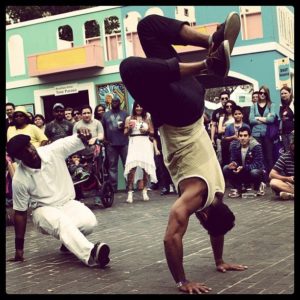 A man doing a handstand on his back while another person watches.
